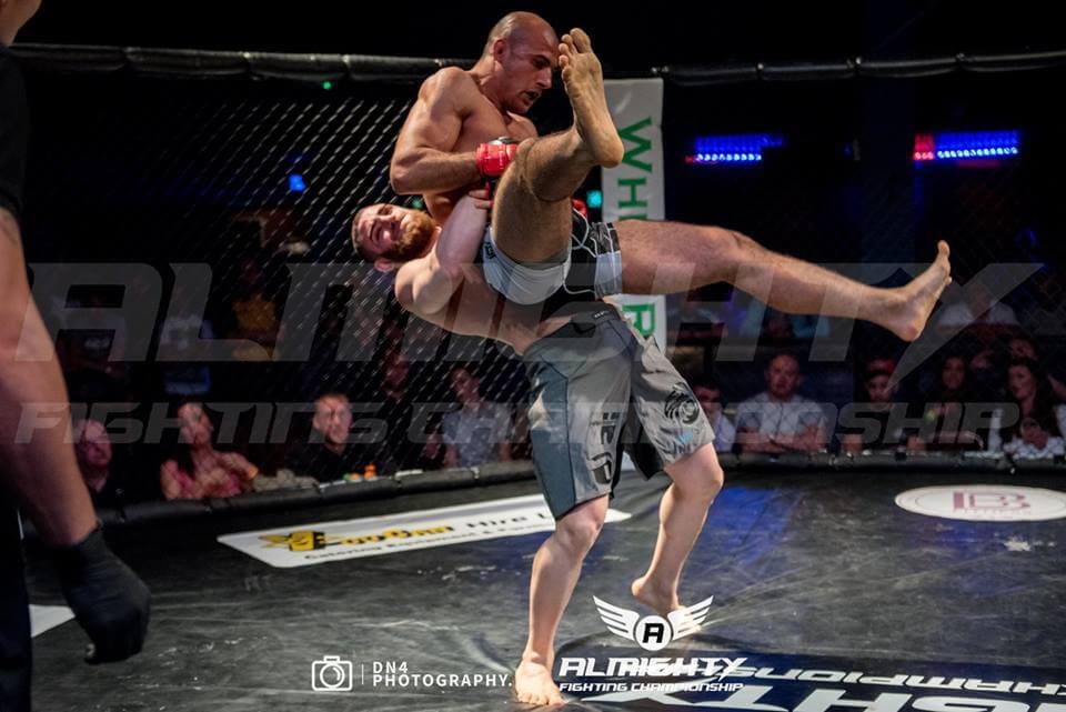 Andreas Tricomitis lifting his opponent for a judo throw during an Almighty Fighting Championship MMA bout