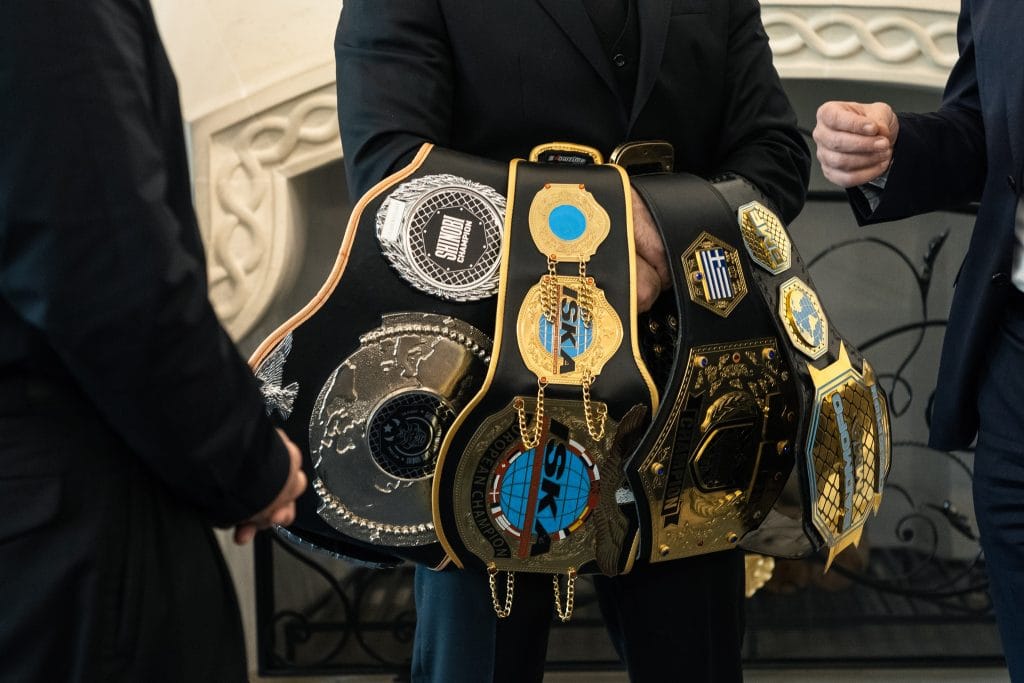 Close-up of Andreas Tricomitis' MMA championship belts, including his Shinobi, ISKA European, EuroBalkan, and BMF World titles